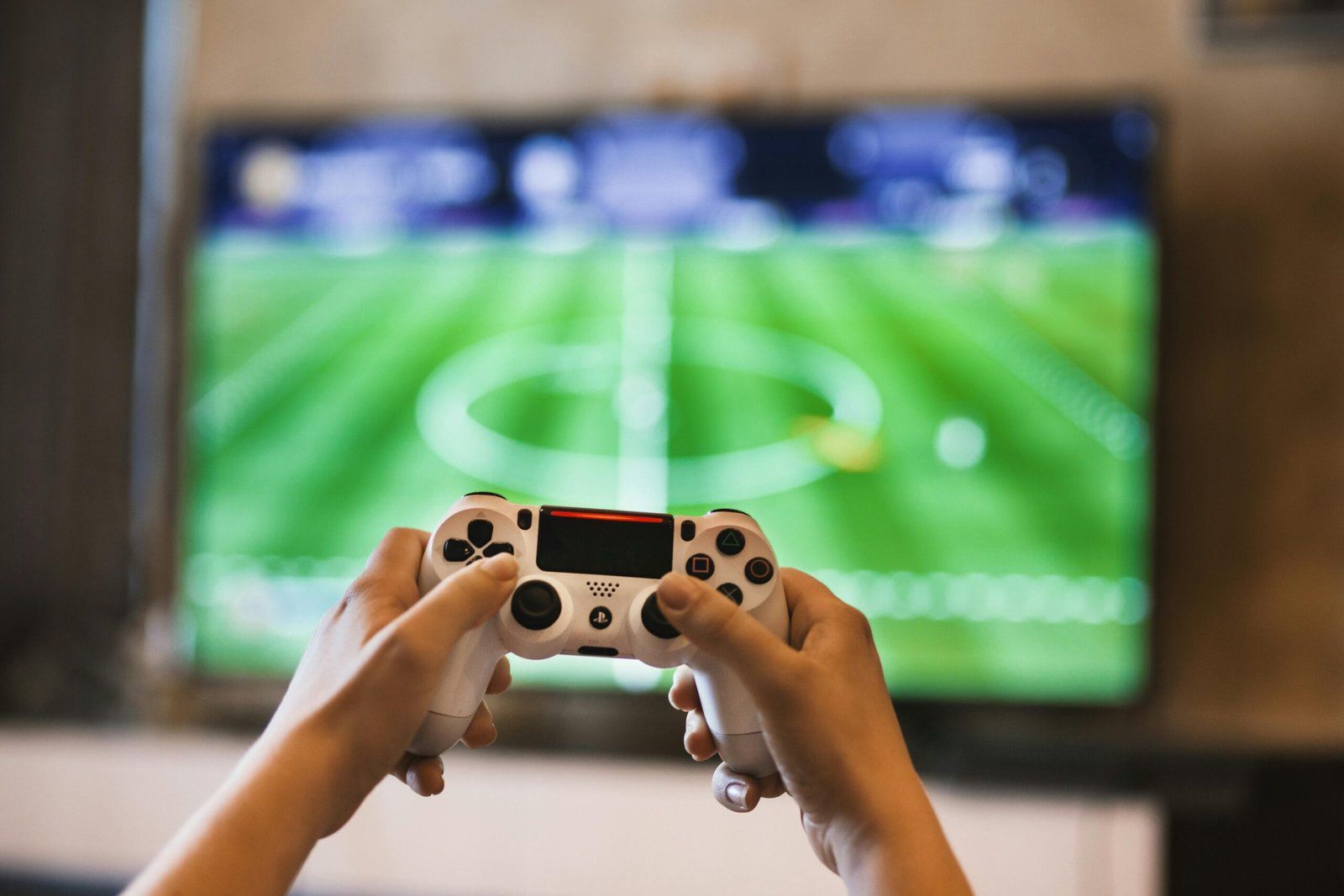 E-sports em Expansão: Os Jogos Competitivos Que Estão em Alta Agora Close-up of hands holding a game controller playing a football video game on screen.