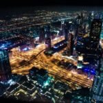 Smart Cities: Como a Tecnologia Está Transformando as Cidades do Futuro A stunning aerial view of Dubai's illuminated skyline at night, showcasing its modern architecture and busy roads.